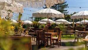 An outdoor seating area with wooden tables and chairs, surrounded by white striped umbrellas. - The Mayflower (Lymington)