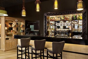 Uma área de bar com balcão, banquetas e diversas garrafas de bebidas.