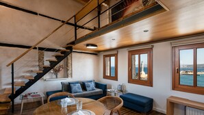 A modern interior with a wooden staircase, a dining area with a round table, and a sofa. - San Salvatore Monastery (Chania)