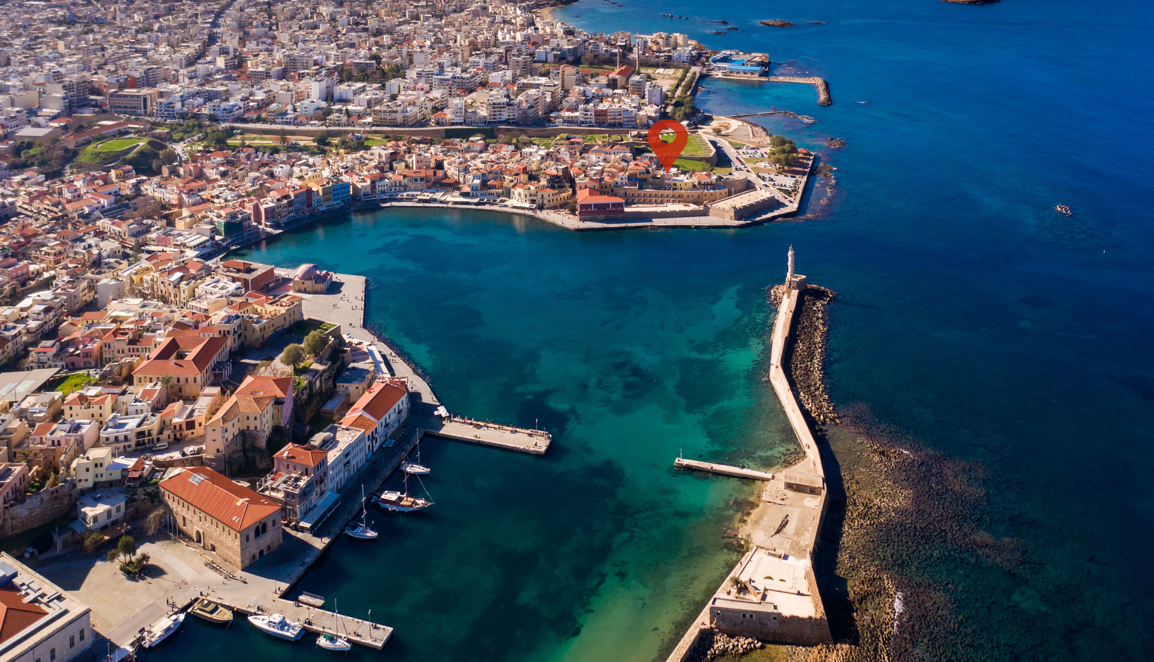 An aerial view of a coastal city with a historic harbor, including a fortified area and a lighthouse.
