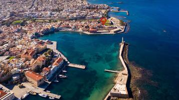 An aerial view of a coastal city with a historic harbor, including a fortified area and a lighthouse.