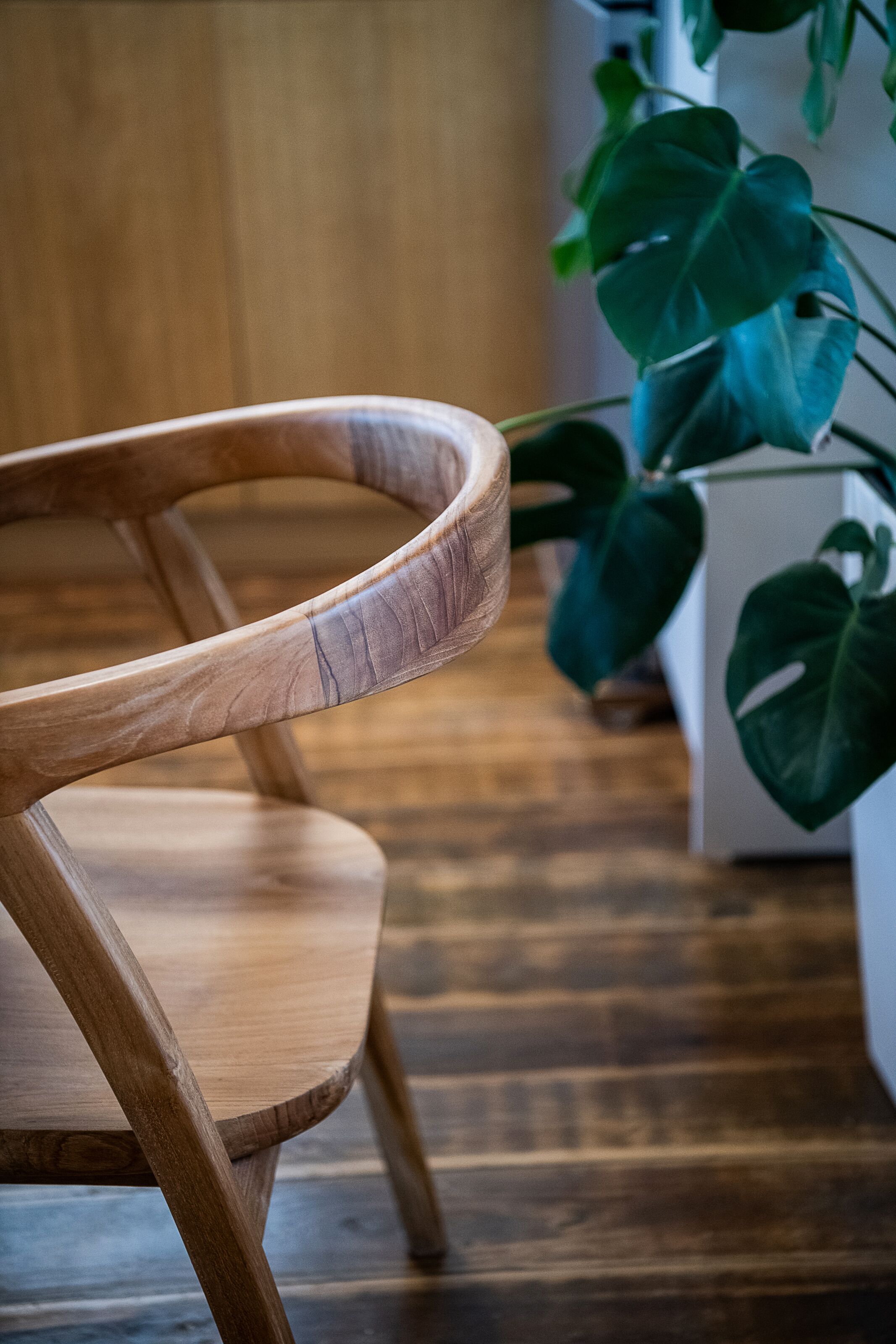Ein Holzhocker mit geschwungener Lehne und Holzboden.
