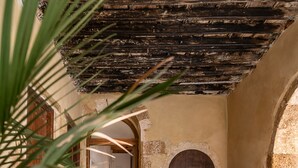 A rustic interior with stone flooring, wooden furniture, and an arched doorway. - San Salvatore Monastery (Chania)