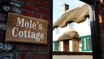 Un letrero de madera con el texto "Mole's Cottage" sujeto a una pared de ladrillo.