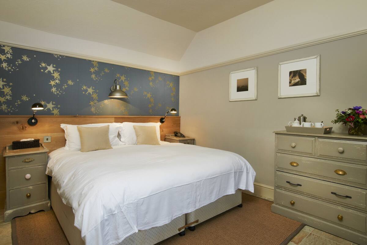 A neatly arranged bedroom with a bed, bedside tables, a dresser, and wall decorations.