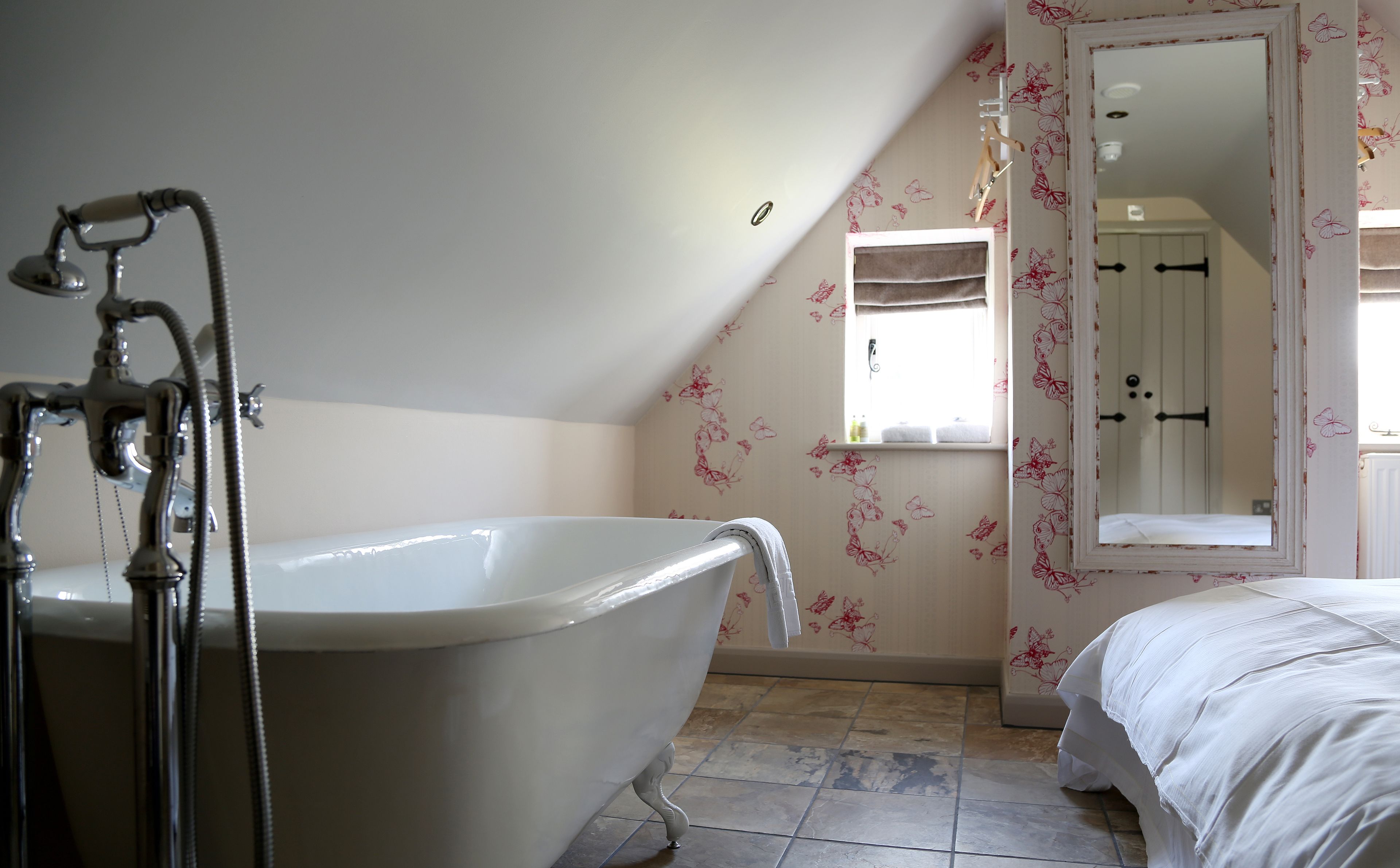Een badkamer met een ligbad op poten, een douche en een spiegel.