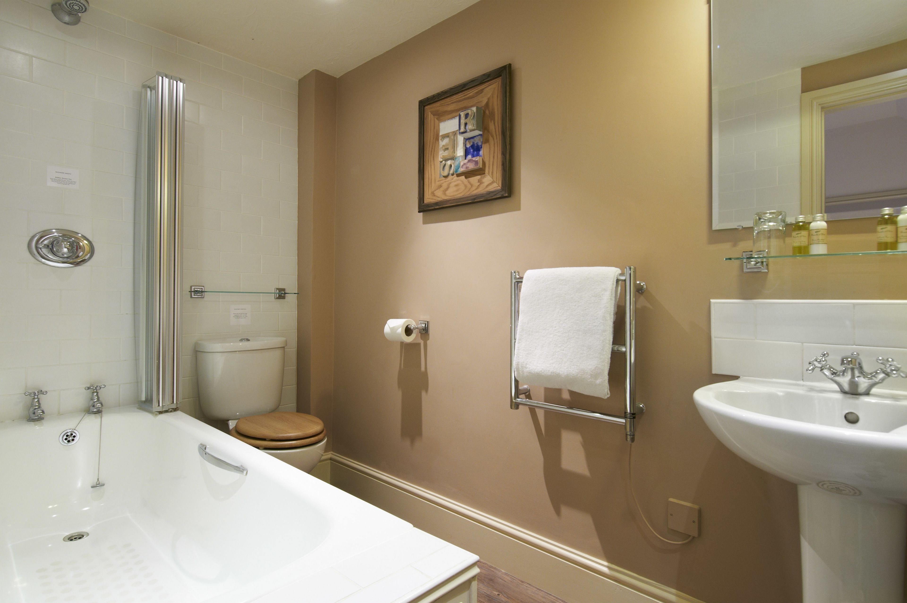 Un baño con bañera, inodoro, lavabo y un cuadro en la pared.