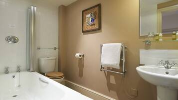 Un baño con bañera, inodoro, lavabo y un cuadro en la pared.