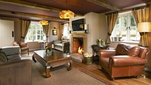 A cozy living room with a fireplace, leather sofas, a coffee table, and a wooden floor. - The Museum Inn (Blandford Forum)