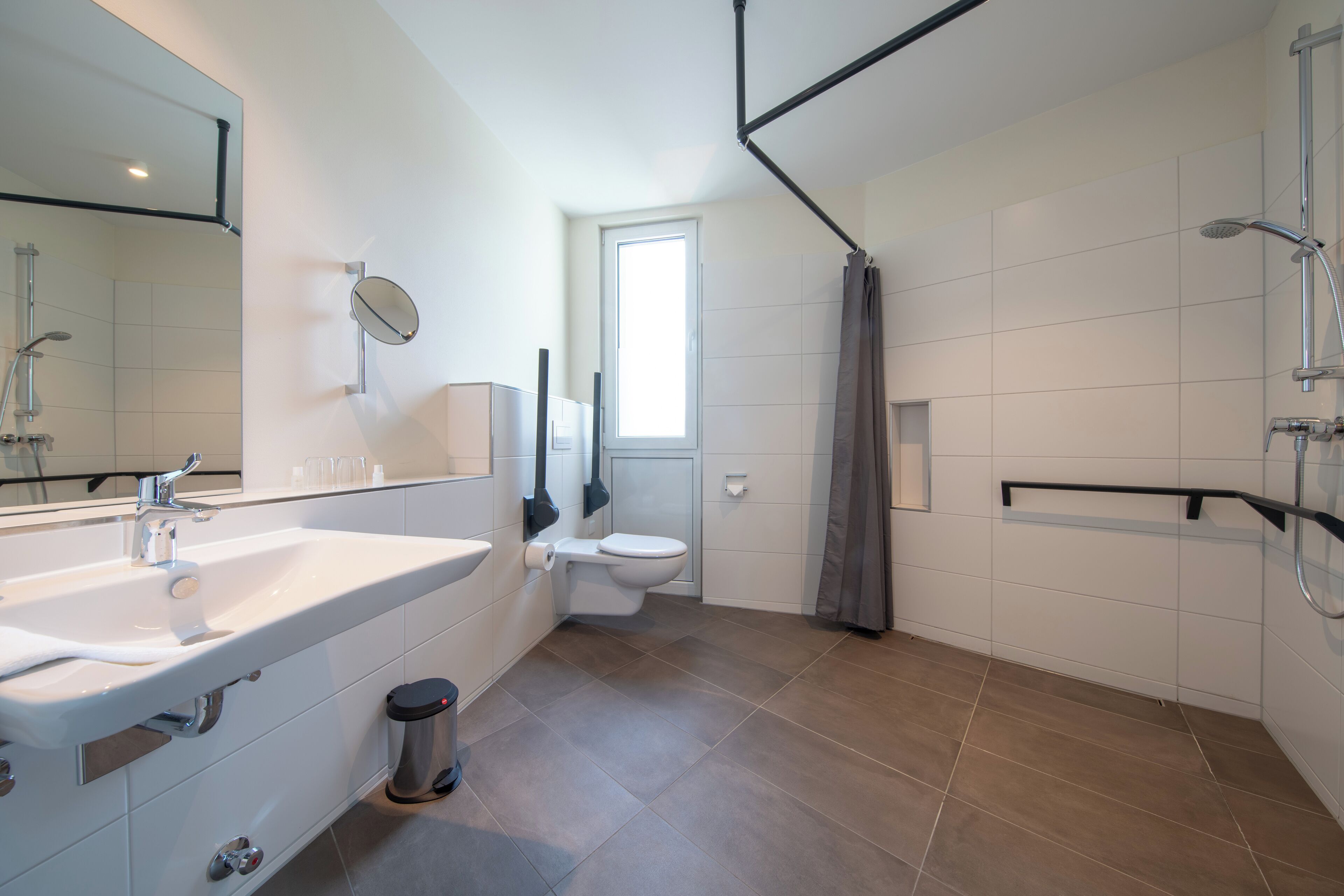 A modern bathroom with a large mirror, a sink, a toilet, and a shower area.