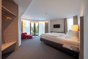 Una habitación de hotel moderna con una cama grande, un escritorio, una silla y un televisor.