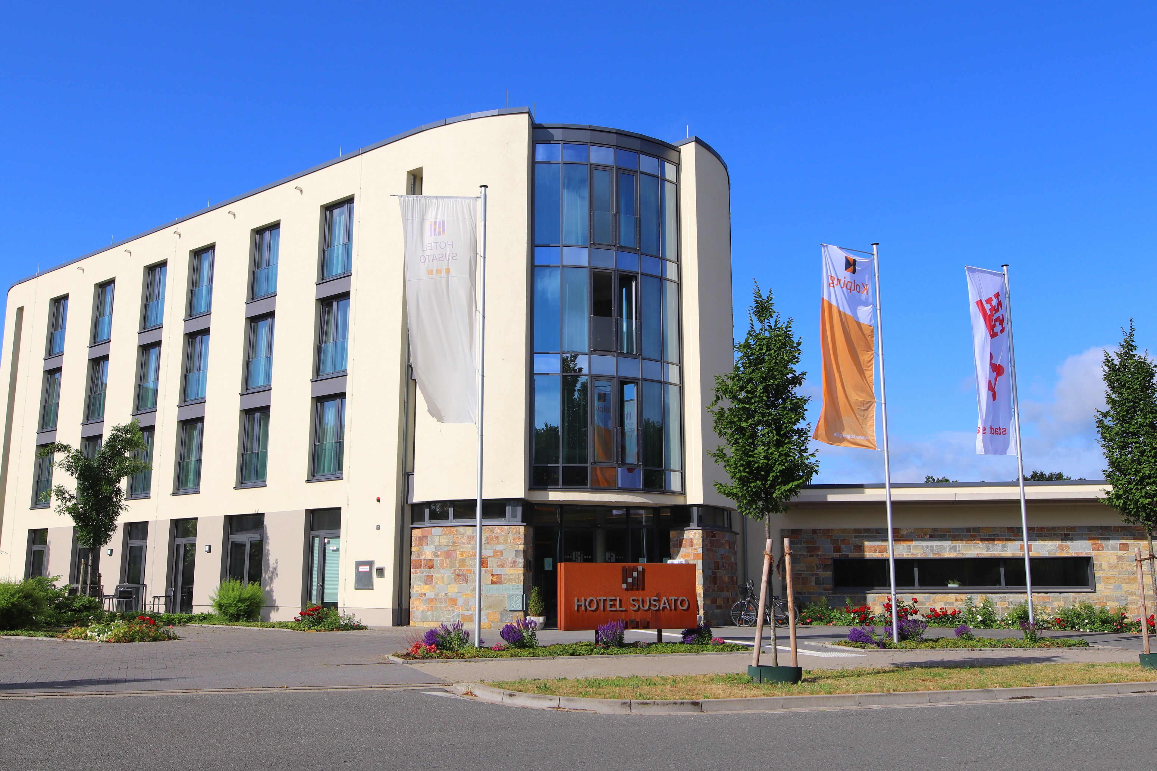 A modern hotel building with a curved facade, multiple windows, and a prominent entrance.