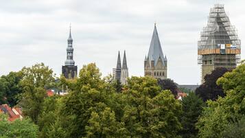 A cityscape with historic buildings, including a church with a tall spire and a building under construction with scaffolding.