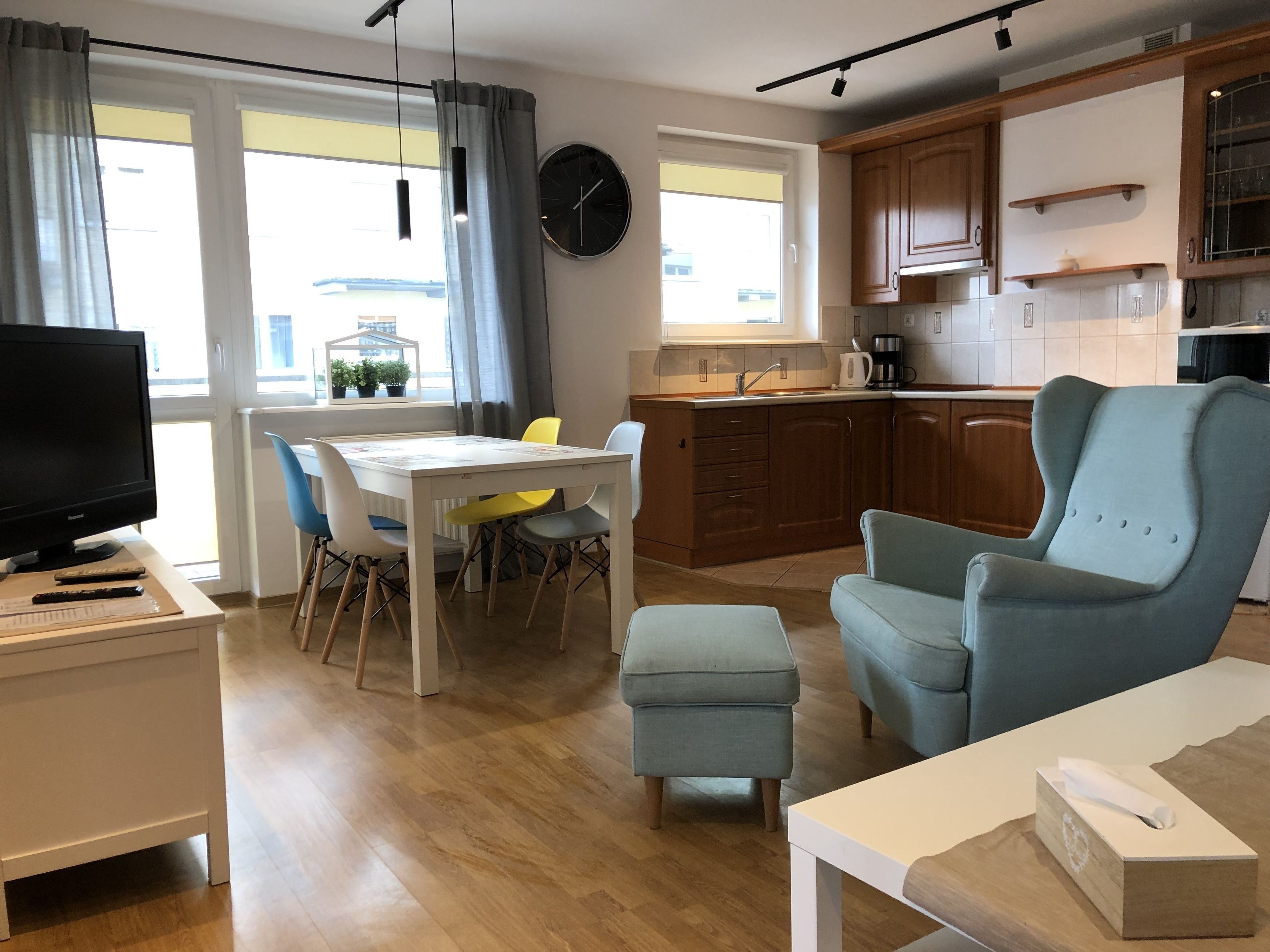 A modern living room with a TV, seating, and a dining area.