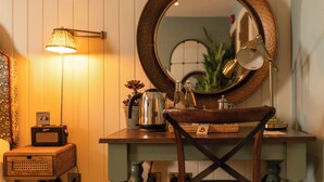 A wooden vanity with a round mirror, a lamp, and a kettle on the counter. - The Old House Inn (Crawley)