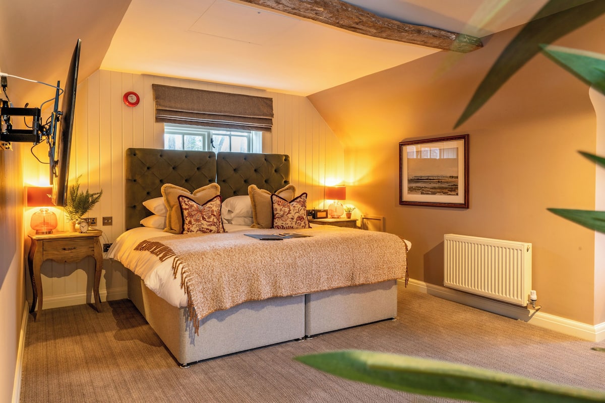 A bedroom with a large bed, two bedside tables, a radiator, and a framed picture on the wall.