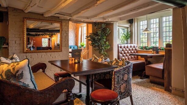 A cozy room with a wooden table, leather chairs, and a large mirror. - The Old House Inn (Crawley)