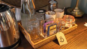 A wooden table with a tray holding various items including a kettle, glass jars, a candle, and a box of Twinings tea.