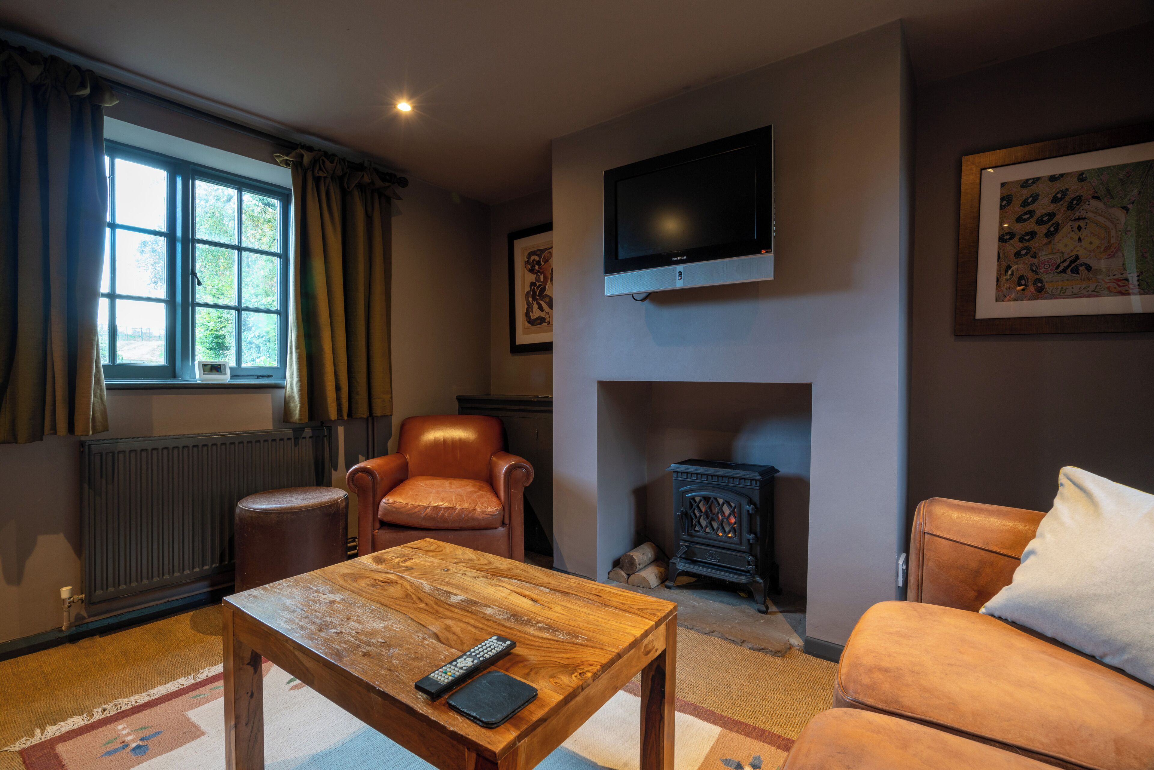 Una sala de estar acogedora con chimenea, un sillón de cuero y un televisor montado en la pared.