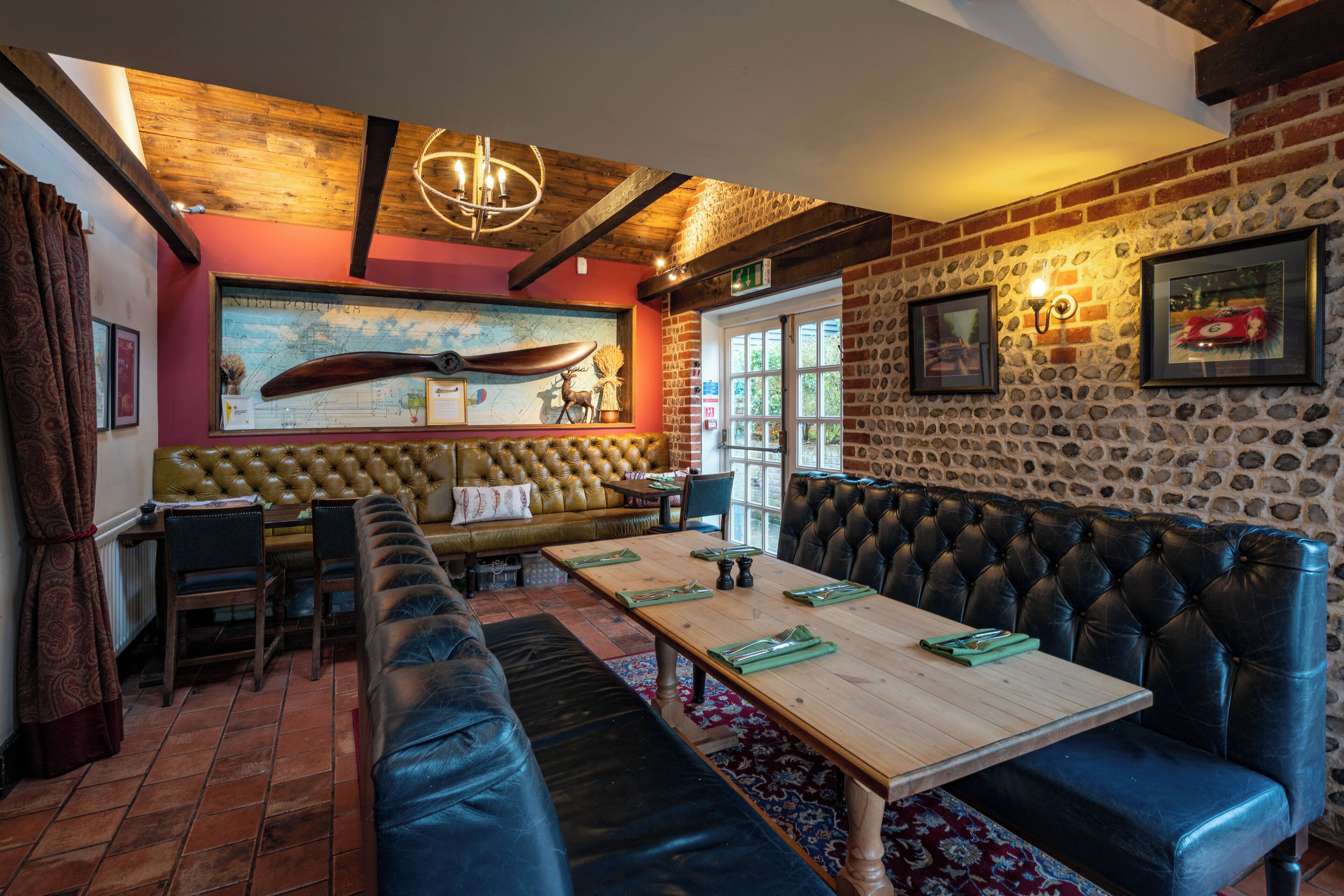 Un restaurante con techo de madera, pared de piedra y asientos de cuero.