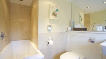 A bathroom with a bathtub, toilet, and a mirror.