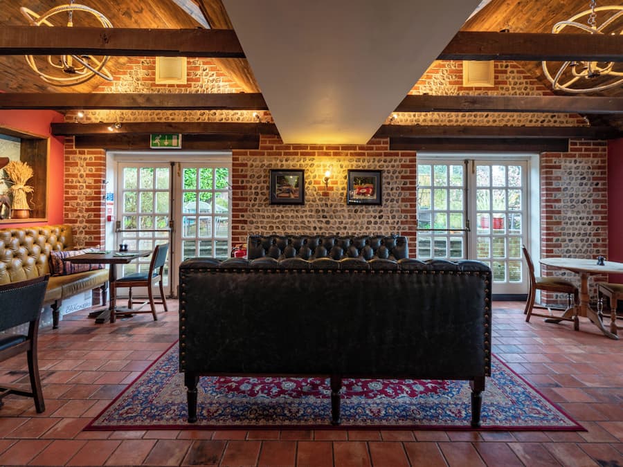 Una habitación acogedora con una cama grande, vigas de madera en el techo, paredes de ladrillo y una chimenea.