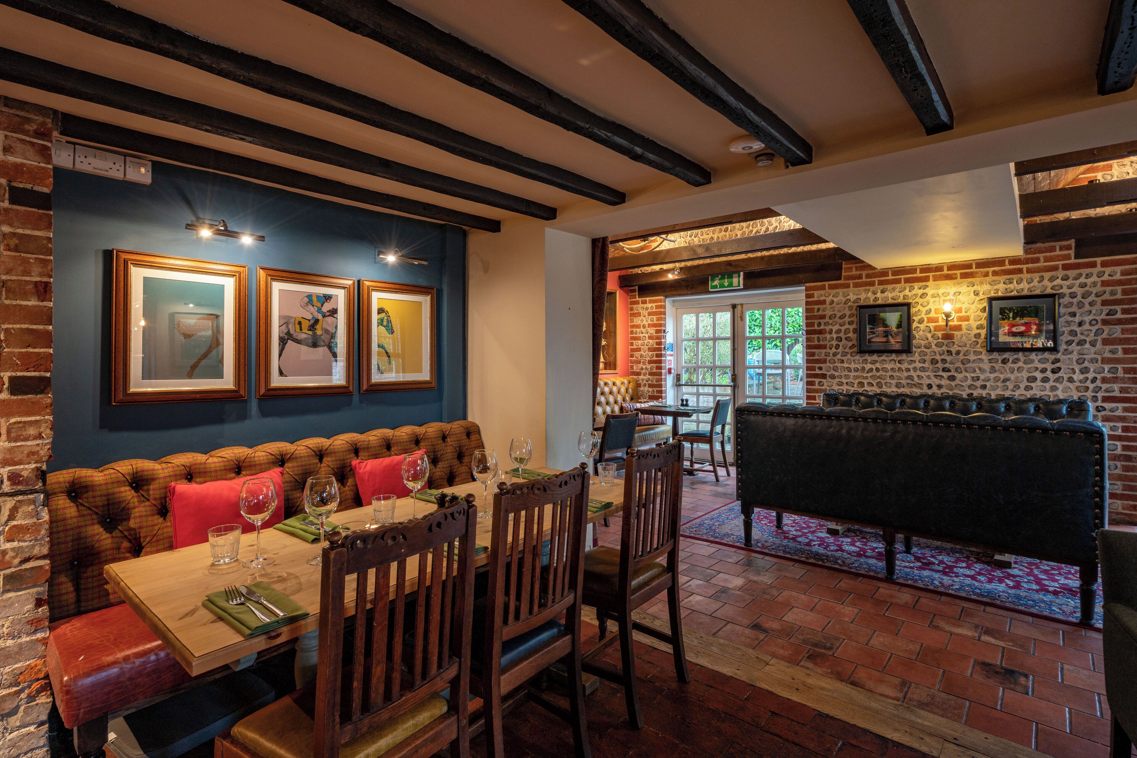 Un restaurant avec un mur en briques, des meubles en bois et des œuvres d’art encadrées.