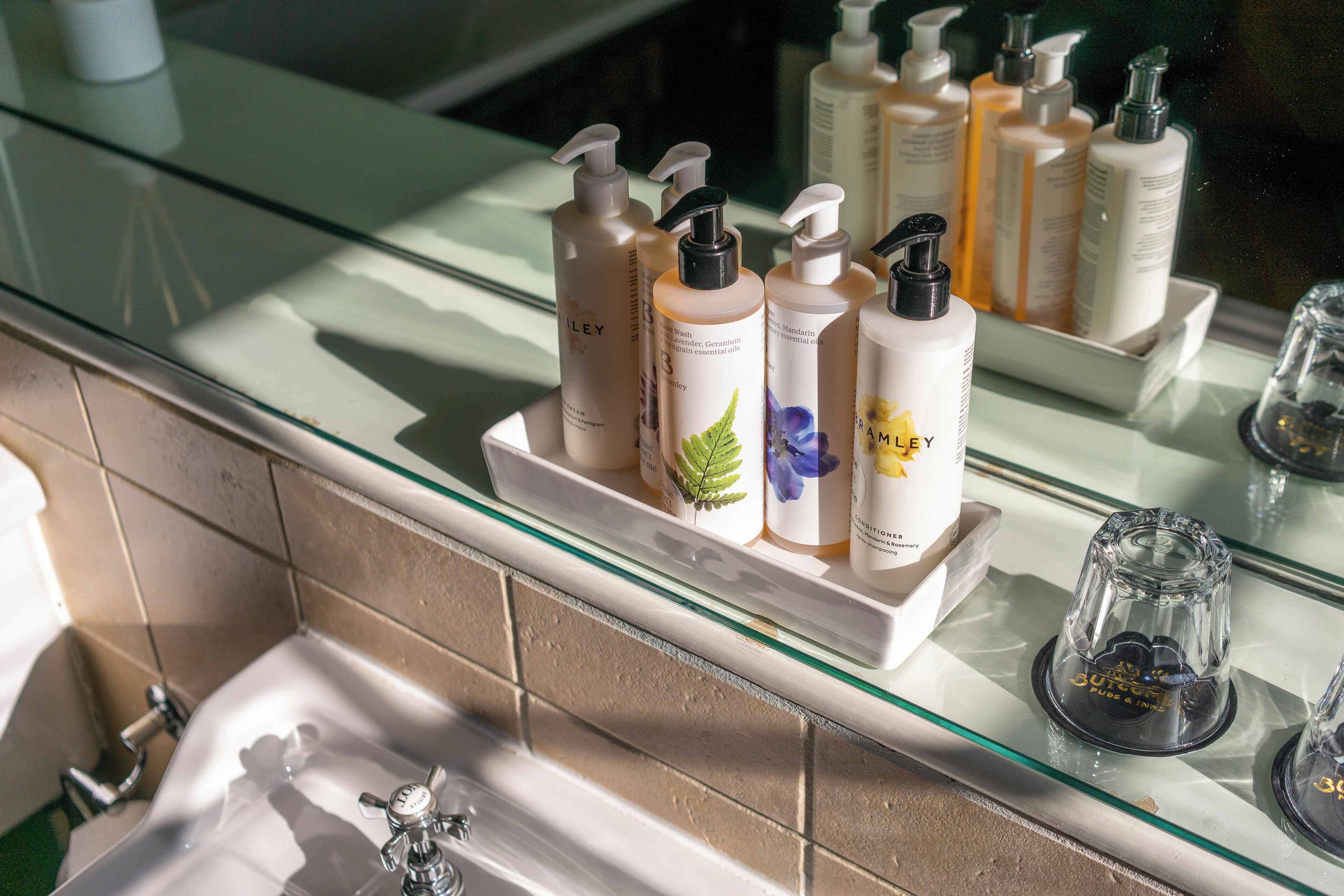 A bathroom with a glass shelf holding various toiletries.