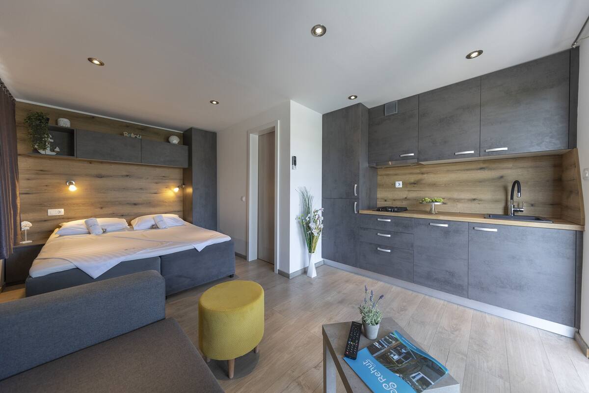 Quarto moderno com cama, mesas de cabeceira e um pequeno espaço de estar.