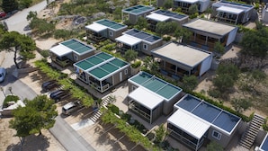 A cluster of modern, compact houses with flat roofs, arranged in a tight formation with a paved driveway and parked cars. - Camp Rehut - Campsite (Murter-Kornati)