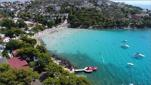 A coastal town with a beach, boats, and residential buildings. - Camp Rehut - Campsite (Murter-Kornati)
