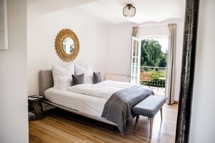Quarto com cama, mesa de cabeceira e vista para o exterior.