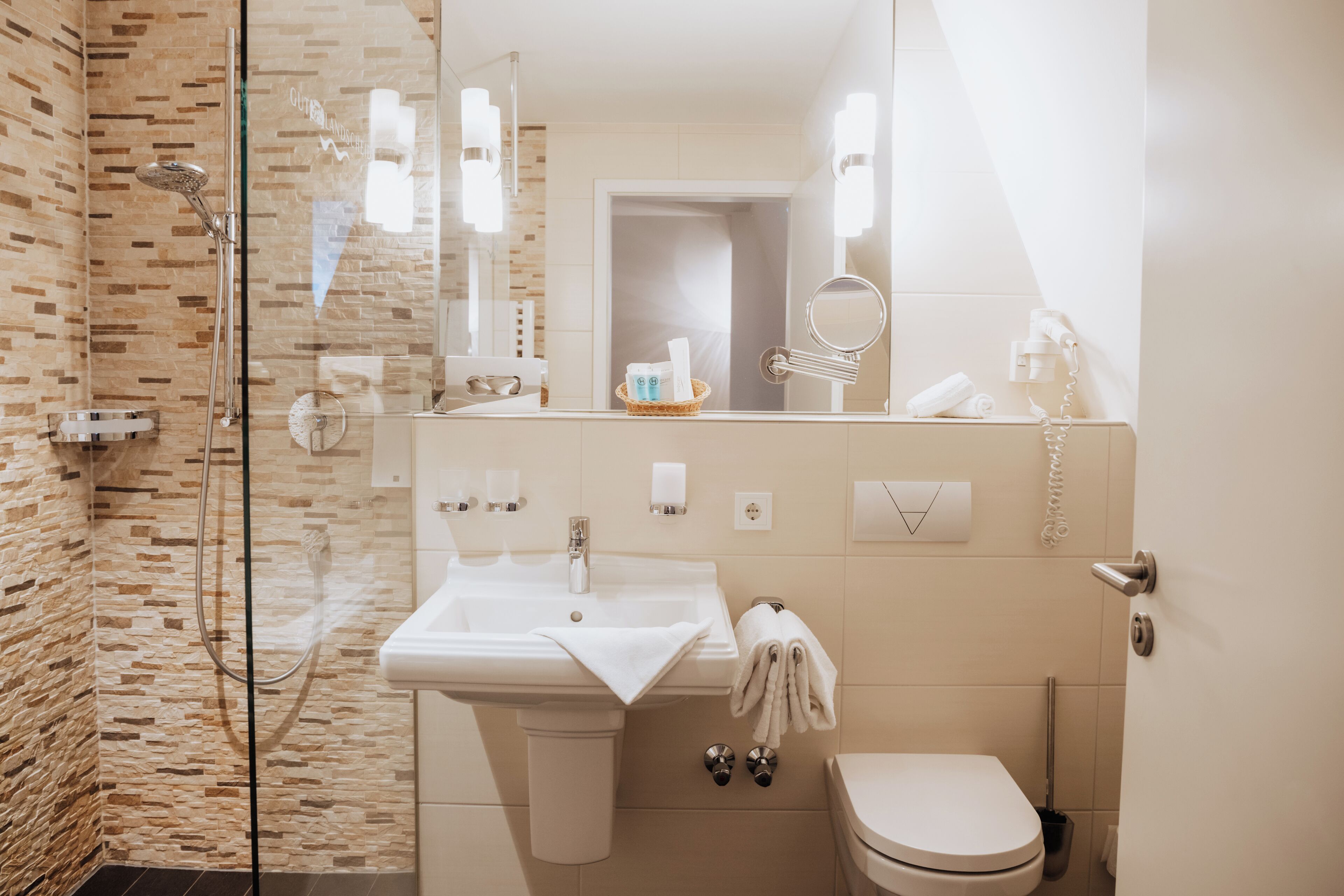 A modern bathroom with a glass-enclosed shower, a sink with a towel, and a toilet.