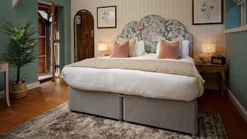 Una camera da letto con un letto grande, una porta in legno, una pianta in vaso e un tavolino con una lampada.