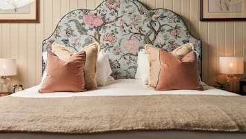 A bedroom with a floral-patterned headboard, multiple pillows, a fluffy rug, and bedside lamps.