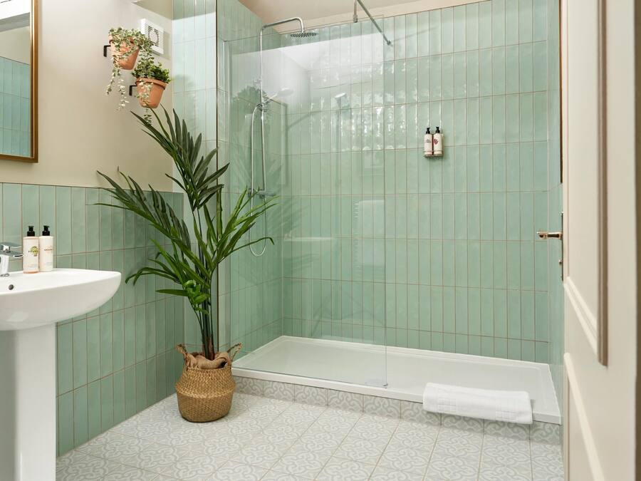 A bathroom with a sink, a shower, and a potted plant.