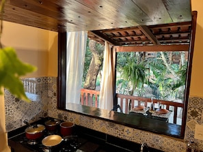 Una cocina con vista a un balcón, una estufa con ollas y un salpicadero con diseño.