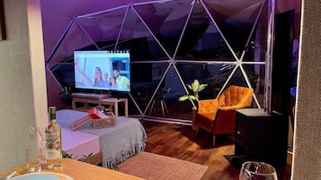 Ein modernes Wohnzimmer mit Fernseher, Sitzgelegenheiten und einem Essbereich.