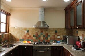 A kitchen with a gas stove, microwave, and stainless steel range hood. - OYO 9625 Home 2BHK Goan Paradise Colva (Betalbatim)