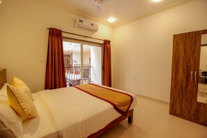 A hotel room with a bed, a wooden wardrobe, and an air conditioning unit. - OYO 9792 Home 2BHK Poolside Siolim (Oxel)