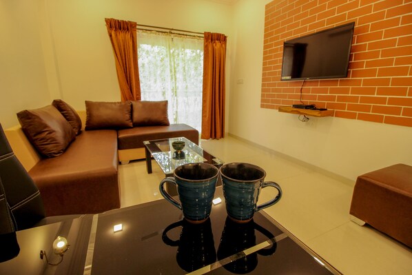 A living room with a sofa, coffee table, and two blue mugs. - OYO 9792 Home 2BHK Poolside Siolim (Oxel)