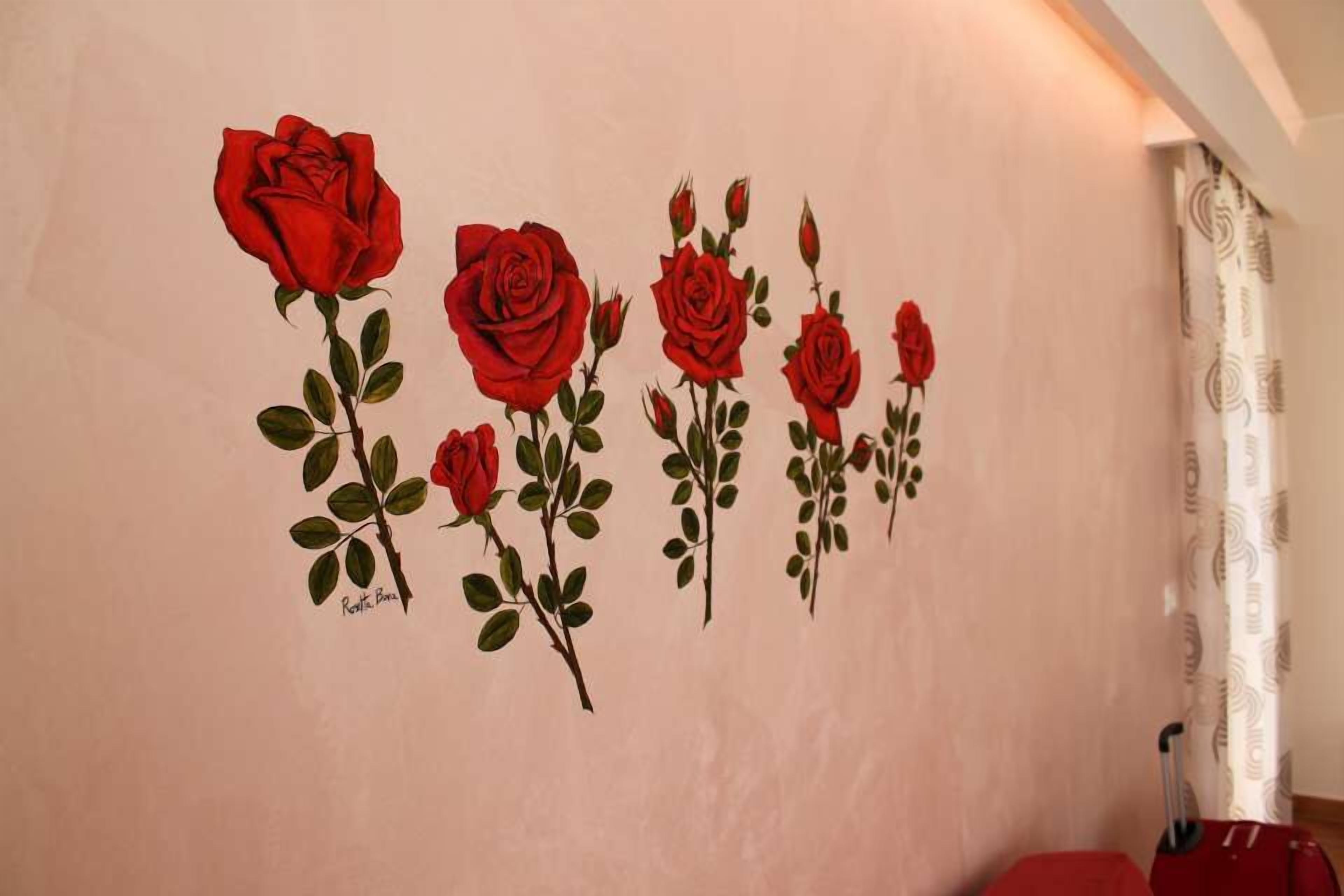 A wall with a series of red roses painted on it.