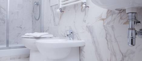 Un baño moderno con inodoro, bidé y lavamanos, todo en color blanco.