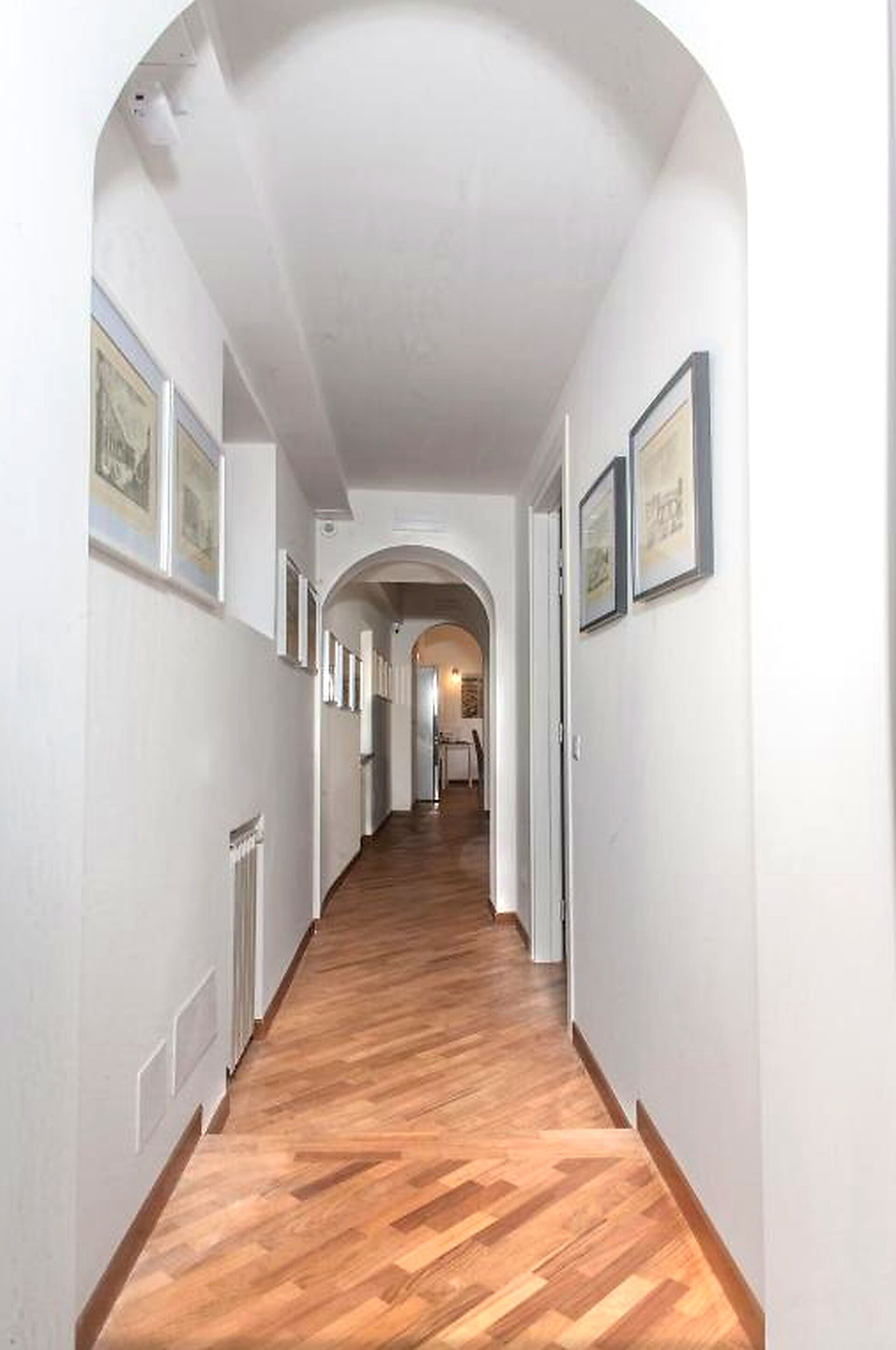 Ein Korridor mit Holzboden, weißen Wänden und gerahmten Bildern.