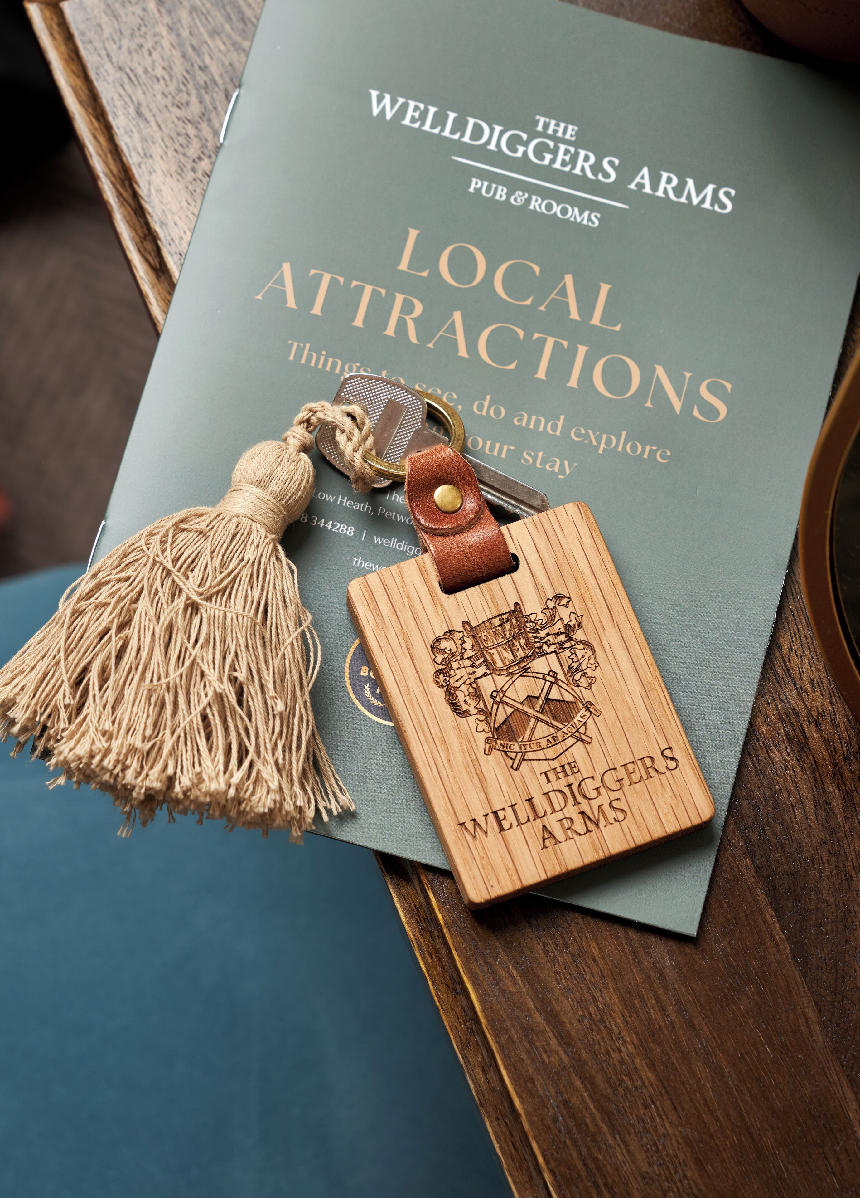 A book titled "The Welldiggers Arms Pub & Rooms" with a wooden bookmark featuring a coat of arms.