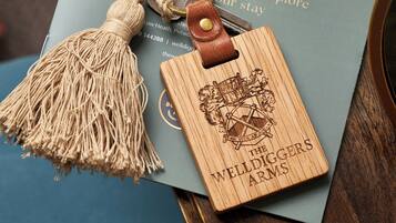 A book titled "The Welldiggers Arms Pub & Rooms" with a wooden bookmark featuring a coat of arms.