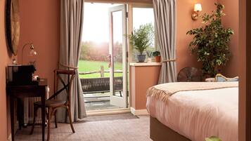 A bedroom with a bed, a desk, a chair, a potted plant, and a view of the outdoors.