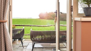 A view from a room with a sliding glass door leading to a patio with two chairs and a potted plant. - The Welldiggers Arms (Petworth)