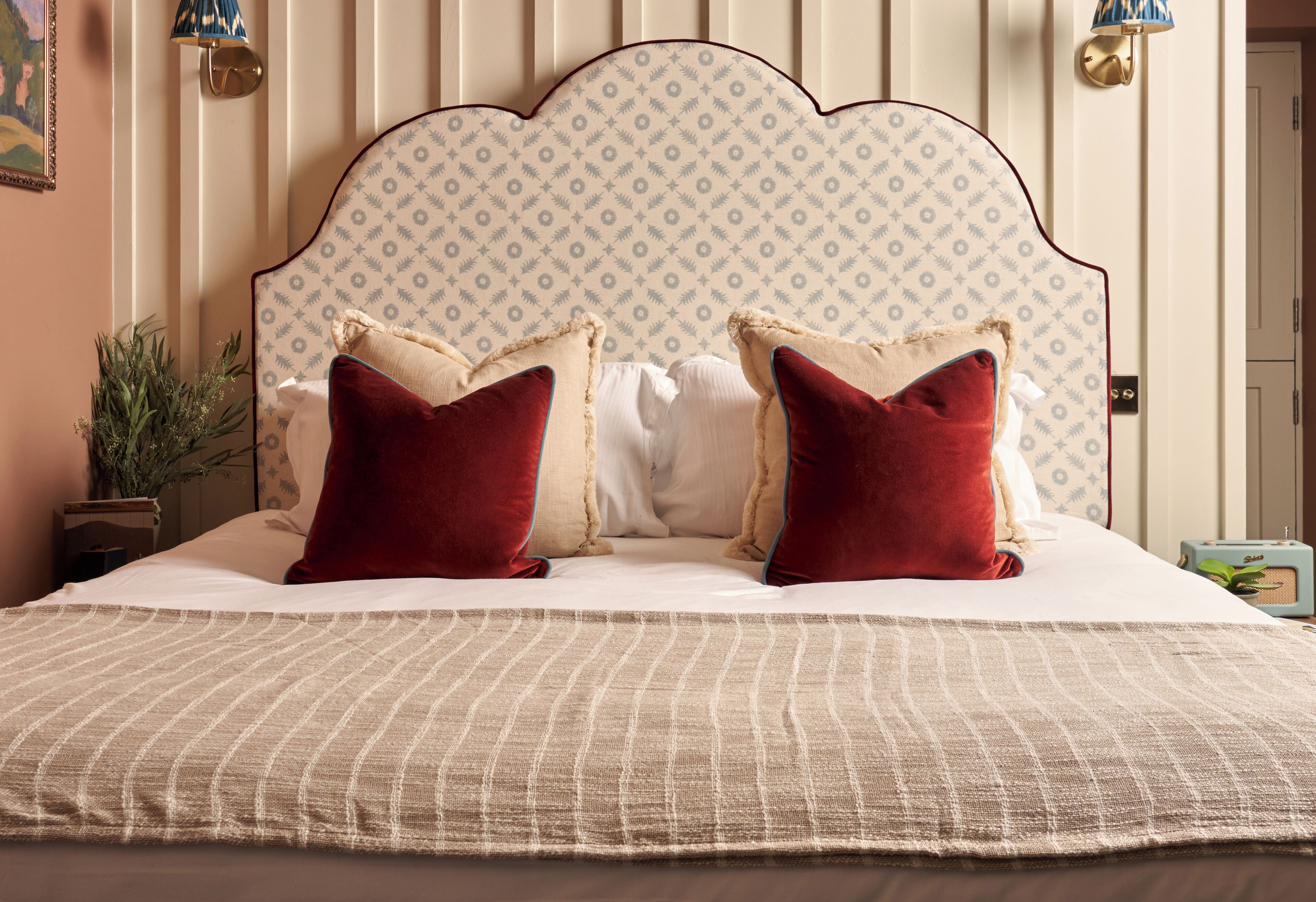A bed with a patterned headboard, two red pillows, and a striped bedspread.