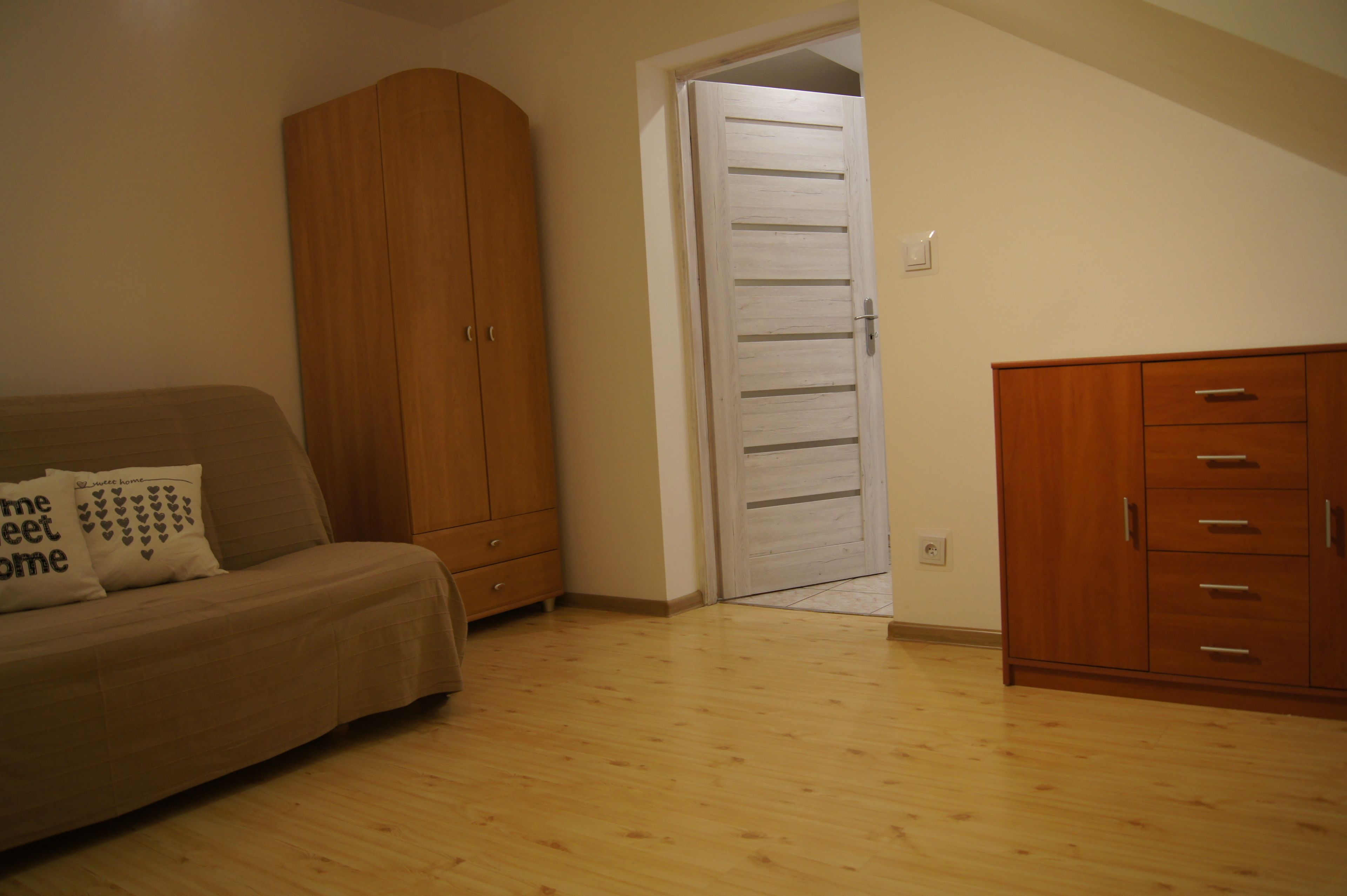 Une pièce comprenant une armoire en bois, un meuble en bois et un canapé beige avec un coussin.